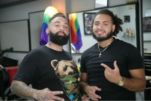 Chago Diaz (Shop owner) and master barber Shawn Oliveras stop cutting hair to pose for a picture.